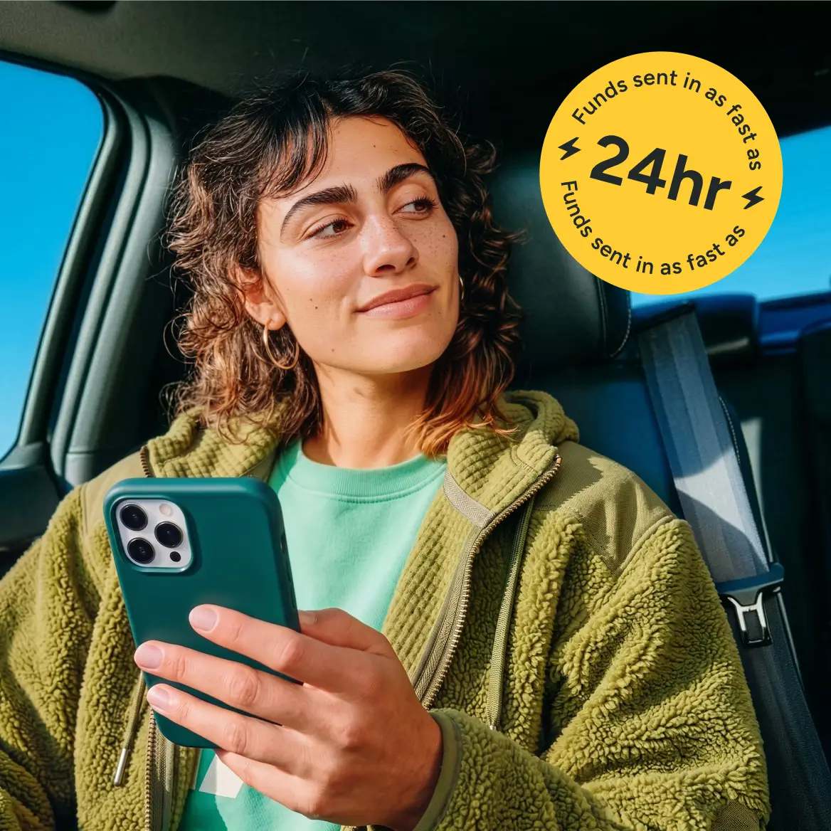 A woman sitting in a car, holding her phone